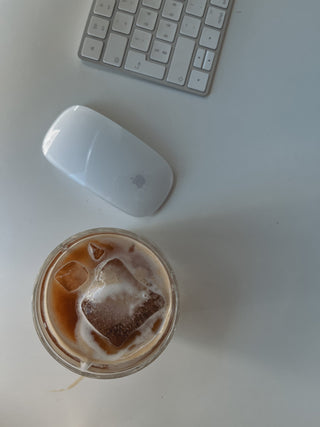 Iced lupine coffee on a desk next to an apple mouse and a keyboard