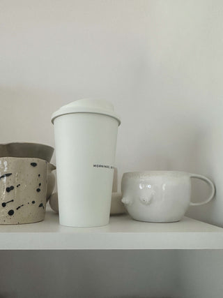Reusable Coffee Cup on a kitchen shelf in white environment with other cups in beige and white
