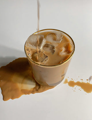 A glass tih iced lupine coffee spilled on white background, minimalistic look.