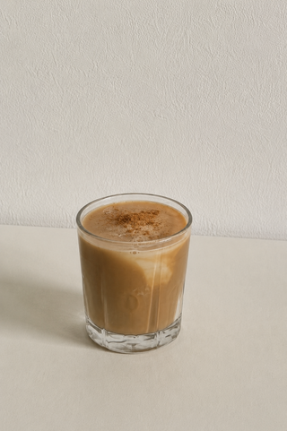 Lulucchino in einem klaren Glas – lupinenbasierter Kaffeedrink mit cremiger Schicht, serviert auf hellem Untergrund.