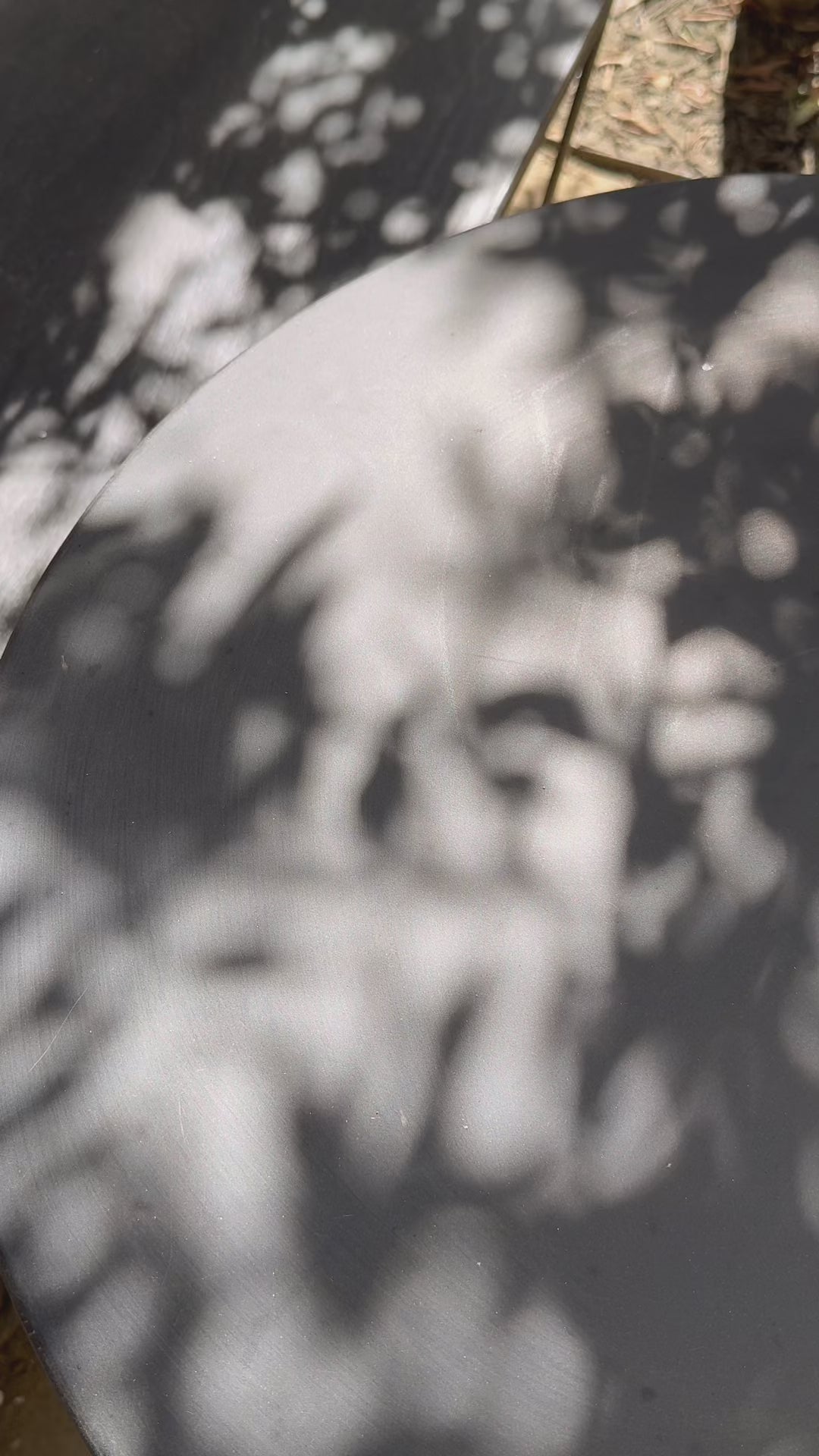 Outdoor concrete table in sunlight with light and shadow close-up of hand placing a iced lupin coffee on it in reuseable plastic cup in summer.